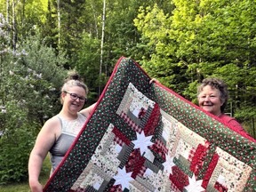 Cassandra Lagassie, left, and her mother Ruth Lagassie proudly display the Christmas quilt they made that the Powassan and District Food Bank is now using as a fundraiser to keep its shelves stocked.