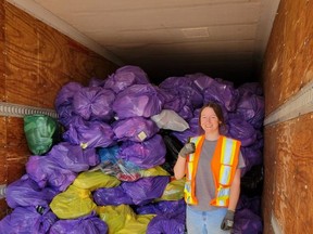 Summer student Ainsley Toner stands next to bags of shoes collected by Strathcona County.
