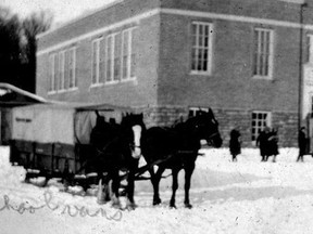 This photograph shows the original way of getting students to school in winter. Horses pulled a canvas-covered sleigh, equipped with a potbellied stove in the middle; students sat on side benches. Pretty good.