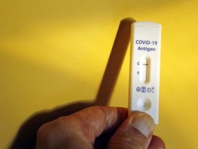 A person holds a COVID-19 rapid antigen testing device showing a negative result.