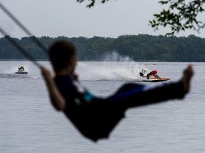 A child spectator plays on a swing as he watches racers compete in Sunday's powerboat races on Stoco Lake in Tweed, Ontario. ALEX FILIPE