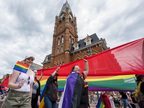 Revelers carry a large rainbow flag as they walk underneath Belleville City Hall during the Bay of Quinte Pride parade on Saturday in Belleville, Ontario. ALEX FILIPE