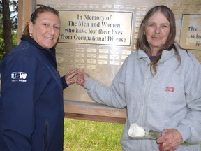 Lise Morin, left, and Veronica Raymond point to a plaque commemorating Lawrence Raymond, the late husband of Veronica and uncle to Morin. He died as a result of chronic obstructive pulmonary disease contracted through his workplace.