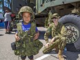 Four-year-old Jaray Mills of Simcoe tries out some military garb thanks to help from Bdr. Luke Brennan of the 56th Field Regiment on Saturday.
