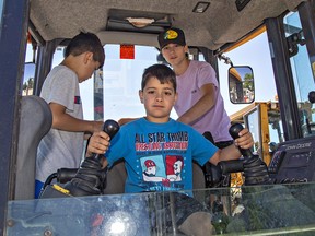 Brothers (left to right) Lucas, Mason and Simon Goncalves check out the cab of a backhoe on Saturday during the Touch-a-Truck event at the arena in Waterford.