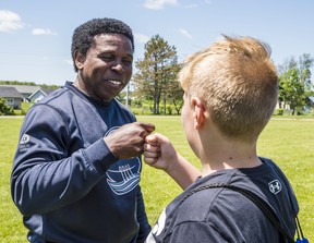 Michael "Pinball" Clemons, General manager for the Toronto Argonauts, fist-bumps an attendee at a flag-football training camp run by the Argos in Tyendinaga Mohawk Territory on Saturday. ALEX FILIPE