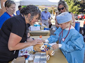 Cardiovascular technologiest Julie Gurney (left) shows Helena, Weatherston, age 9 how to prepare her teddy bear for blood work at a station designed to alleviate children's fears of being treated in hospital, during the 100th anniversary party for the Willett Hospital on Wednesday in Paris.