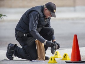 A member of the Special Investigations Unit places a tuque that appears to be stained with blood in an evidence bag on Oct. 28, 2021, after a London police officer shot and killed Justin Bourassa, 29, behind a plaza on Richmond Street near Pall Mall Street in London. (Derek Ruttan/The London Free Press)