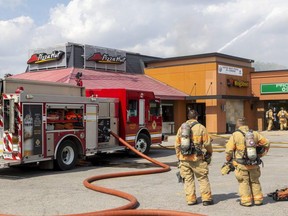 London firefighters survey the damage after fire burst through the roof of the Pizza Hut restaurant on Huron Street at Highbury Avenue on Tuesday, May 31, 2022. (Mike Hensen/The London Free Press)
