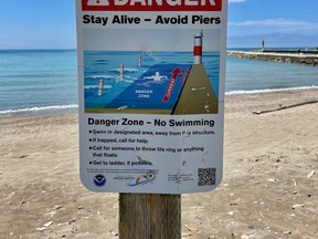 This sign warns of the danger of swimming near the south pier, which can be seen in the background at Station Beach in Kincardine, Ont. on Wednesday, June 29, 2022. (Dave Jenkins photo)