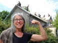 Farmer Michele Vindum flexes her arm Thursday as a crew of female roofers replaces the roof of her Plainfield home. Vindum's search for one female roofer snowballed into a national female roofing crew now called the Summit Sisters.