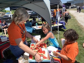 Halle Sitarski of the Grand Erie District School Board's Indigenous education program, serves watermelon slices to Crimson Rose Martin, in orange shirt, and Breanna General, both 7, during Solidarity Day festivities on Tuesday at the Six Nations Sports and Cultural Memorial Centre in Ohsweken. The day, known as National Indigenous Peoples Day across the country, included music, midway rides and food.