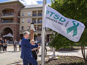 Brantford mayor Kevin Davis and Kimberlee Taplay of Project Dragonfly raise a flag to mark PTSD Awareness Day on Monday at Harmony Square in downtown Brantford.