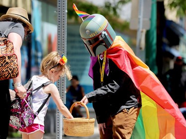 Evan Martin, right, stops while Lena Walsh, 6, grabs a Pride goodie while her mom, Melissa Wood-Walsh, looks on during  Brockville's eleventh annual Pride Parade on Saturday morning. (RONALD ZAJAC/The Recorder and Times)