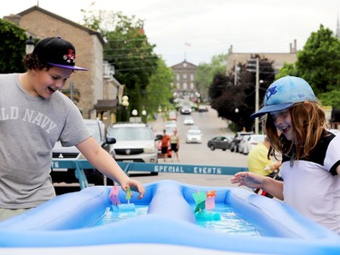 Jackson, left, and Charlie Hopkins, of Ottawa, cheer on their vessels in the "Raingutter Regatta" children's activity on Broad Street Sunday afternoon. (RONALD ZAJAC/The Recorder and Times)