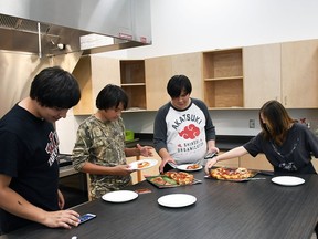 Wallaceburg District secondary school students Williams Sands, Evander Wiman, Turtle Loulas and Faith Corbiere-Logan enjoy some pizza after school in the kitchen area of the student hub Wednesday. (Tom Morrison/Postmedia Network)