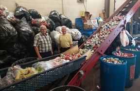 Achom Shrine Club members Dennis, left, and Fred Knight display the conveyor line on the “mother of all can crushers.”  The club crashes 40,000-plus pounds of pop cans annually that are sent to a smelter in Kentucky with the proceeds going to the Shriner's Hospital for Children in Montreal.  (Ellwood Shreve/Chatham Daily News)