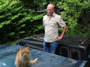 Cornwall resident John Parette, with his own cat Trigger on top of the truck cap in his yard where underneath it he recently discovered three newborn, abandoned kittens. Photo on Thursday, June 9, 2022, in Cornwall, Ont. Todd Hambleton/Cornwall Standard-Freeholder/Postmedia Network