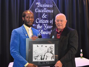 From left, Chamber's Citizen of the Year Lee Theodore accepts his plaque, with art created by Jordan Thompson, from last year's winner Stephen Douris on on Thursday June 23, 2022 in Cornwall, Ont. Shawna O'Neill/Cornwall Standard-Freeholder/Postmedia Network