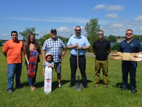Locals gathered to break ground at the Akwesasne Skatepark, including the following, from left to right: A'nowara'ko:wa Arena manager Mark Martin, MCA director of economic development Kylee Tarbell (holding a board painted by Akwesasne's Jake Oakes), Kawehno:ke District Chief Vince Thompson (with young skater Rain), Grand Chief Abram Benedict, MCA business support officer Troy Thompson, and Kawehno:ke District Chief Edward Roundpoint (holding a board wood burned by Akwesasne's Tekaronhiakwas McDonald). Pictured on Friday June 24, 2022 in Akwesasne, Ont. Shawna O'Neill/Cornwall Standard-Freeholder/Postmedia Network