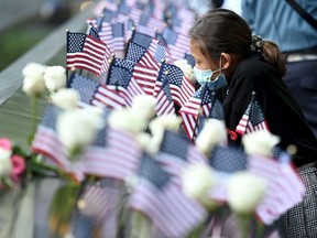A family member at the reflecting pool places a flag during a ceremony at the National September 11 Memorial and Museum on Sept. 11, 2021, in New York City. David Handschuh/Getty Images