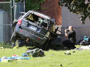 A Kingston Police investigator photographs a Ford Escape that collided with a tree behind Normandy Hall, located just east of the LaSalle Causeway in Kingston on Monday.