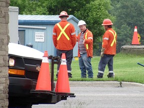 A Utilities Kingston crew discuss the west-end sewer main break at Front Road and Days Road near Centre 70 Arena on Thursday.