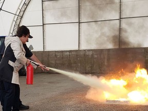 South Huron staffer Sue Johnson extinguishes a fire under the guidance of fire prevention officer Mike Herbert. Handout