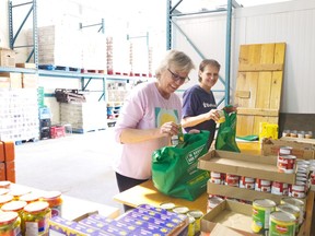 Cathy Beaton, left, and Nicky Therriault pack food bags in the warehouse of the Cochrane Food Bank. Since December, the Cochrane Food Bank has seen a huge increase in the number of clients using its services. HEATHER BROUWER