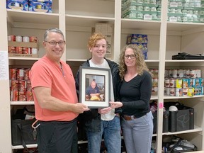 From left, St. Joseph's Food Bank President Rene Lachapelle, Kaleb Staley and Kimberley Mitchell, hold a photo of the late Kole Raymond. Previous to his death last year, Kole would identify people in need of food and other necessities in the community and anonymously buy and deliver them groceries. His family, Kaleb (brother), Kimberley (mother) and sister Kassy (not in photo) held a fundraiser in Kole's name, raising $2,710 for the food bank.