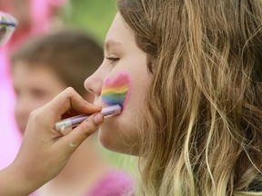 Ella Weisgerber, 11, gets a rainbow-coloured heart painted on her cheek courtesy of Isabella Vernon during the first St. Marys Pride Day Sunday afternoon at Milt Dunnell Field. (Cory Smith/Stratford Beacon Herald)