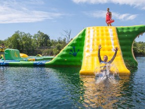 Lifeguard Jarod Medd keeps an eye on St. Marys Mayor Al Strathdee as he enjoys the new inflatable waterpark opening at the St. Marys Quarry on Saturday.  St. Mays events co-ordinator Andrea Macko is capturing the moment.  Chris MontaniniStratford Beacon Herald