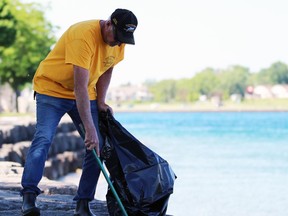 Ross Bishop, organizer of the Bluewater Anglers' annual shoreline cleanup, picks up garbage near the club's hatchery on Saturday, June 11, 2022 in Point Edward, Ont.  Terry Bridge/Sarnia Observer/Postmedia Network