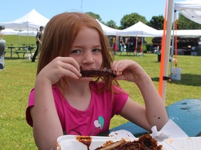 Bella Holmes, 6, munches on a rib Friday as her family stopped lunch at the Sarnia Kinsmen Ribfest in Centennial Park.  (PAUL MORDEN/The Observer)