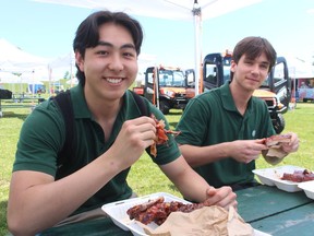 Kenny Gudz, left, and Hayden Pereira, students at St. Patrick's Catholic high school, have lunch Friday at the Sarnia Kinsmen Ribfest in Centennial Park.  (PAUL MORDEN/The Observer)