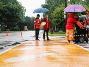 Nim Plain, from the Aamjiwnaang First Nation, performs Monday during a dedication ceremony for a new orange Cathcart Boulevard crosswalk, commemorating Indigenous children taken from their families and forced into residential schools. (Terry Bridge / Sarnia Observer)
