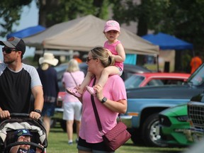 Marie Hull, of Sarnia, walks with her daughter Paige Hull, 2, on her shoulders Sunday at Sarnia’s Canatara Park during Cruise in the Park.
