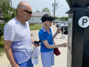 George and Heather Ewart-Cooper of Hamilton attempt to use a pay station for parking on Walker Street in Port Dover on Wednesday. Norfolk County has introduced a new parking pilot project in three of its lakeside communities. George gave thumbs down to the system. Wednesday was the first day for the program. SIMCOE REFORMER PHOTO