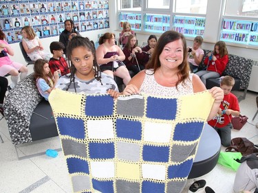 Ariah Wilson, 9, and teacher Francine Portelance display a knitted blanket created by students in the Knitting Club at Chelmsford Valley District Composite School in Chelmsford, Ont. on Wednesday June 15, 2022. More than 30 elementary school students from the school have been working on their knitting skills before classes start in the morning and during recess, and at the same time, contributing to knitted blankets for cancer patients at the Northeast Cancer Centre. The Knitting Club students, lead by Portelance, presented four blankets to Tannys Laughren, lead of Volunteer Services at Health Sciences North. John Lappa/Sudbury Star/Postmedia Network