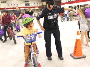 Timmins Police assistant officer Tammy Grydsuk teaches the left turn hand signal to Seth Keen at the Helmets on Kids bike rodeo held Thursday at the Archie Dillon Sportsplex.  Thursday's event was the first time the TPS annual bike rodeo was held in conjunction with Helmets on Kids.  Lead sponsor Girones, Bourdon, Kelly intends to make it an annual event.  NICOLE STOFFMAN/The Daily Press