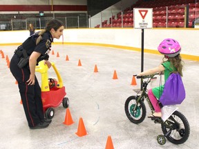 Timmins Police Const.  Caroline Rouillard uses a toy car to simulate oncoming traffic to teach Samantha Keen about the oncoming traffic road sign at the Helmets on Kids bike rodeo on Thursday.  NICOLE STOFFMAN/The Daily Press