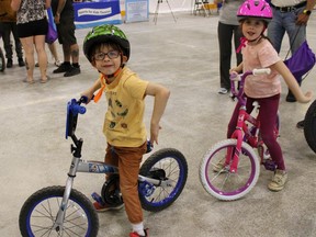 Seth Keen demonstrates the hand signal for stopping as his sister Samantha looks on.  The siblings are wearing new bike helmets provided by lead sponsor Girones, Bourdon, Kelly, to promote safe cycling from a young age.  NICOLE STOFFMAN/The Daily Press