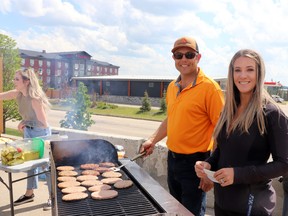 Lance Crawford and Kait Moffat of New Venture Safety Services worked over the grill while Riley Shepherd, far left, served food.
