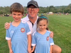 Sudburnia Soccer Club technical director Brian Ashton poses for a photo with young players Elliot Cropp and Amelia Muscolino while action continues at Rotary Park in Sudbury.