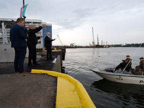 Kingston Police investigators speak with the Ontario Provincial Police Underwater Search and Recovery Unit near Crawford Wharf on Tuesday afternoon in Kingston.