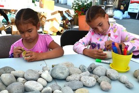 Steve Lavalley, 4, left, and Frankie Lavalley, 6, of Cape Croker color river rocks outside Upwards Art Studio during the hottest street sale along East 2nd Avenue on Saturday July 9, 2022 in Owen Sound, Ontario.  It was the 32nd edition of the event and the first time it had been held since 2019.