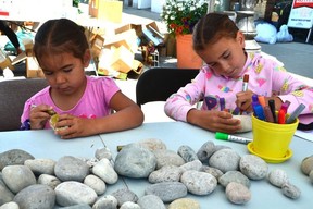 Steve Lavalley, 4, left, and Frankie Lavalley, 6, of Cape Croker color river rocks outside Upwards Art Studio during the hottest street sale along East 2nd Avenue on Saturday July 9, 2022 in Owen Sound, Ontario. It was the 32nd edition of the event and the first time it had been held since 2019.