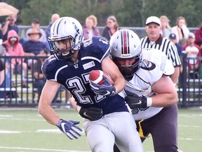 Sudbury Spartans running back Owen Ingram (27) fights for yardage while being tackled by the North Bay Bulldogs' Gabriel Charlebois (99) during Northern Football Conference action at James Jerome Sports Complex in Sudbury, Ontario on Saturday, July 9, 2022.