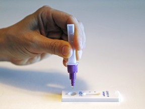 A person squeezes a drop of testing solution into a COVID-19 rapid antigen testing device.