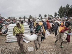 In this file photo taken on Sept. 15, 2021, men carry a sack of wheat during a food distribution by the World Food Program for internally displaced people in Debark, 90 kilometres from the city of Gondar, Ethiopia.